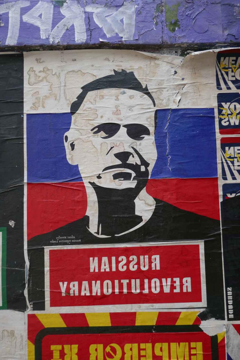 Street art featuring a black and white rendering of Alexei Navalny in front of a Russian flag and with the words "Russian Revolutionary" underneath.